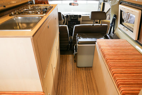 Closer look at Desert-Tec Land Cruiser interior with dual-burner stove, sink, fridge, seating and storage