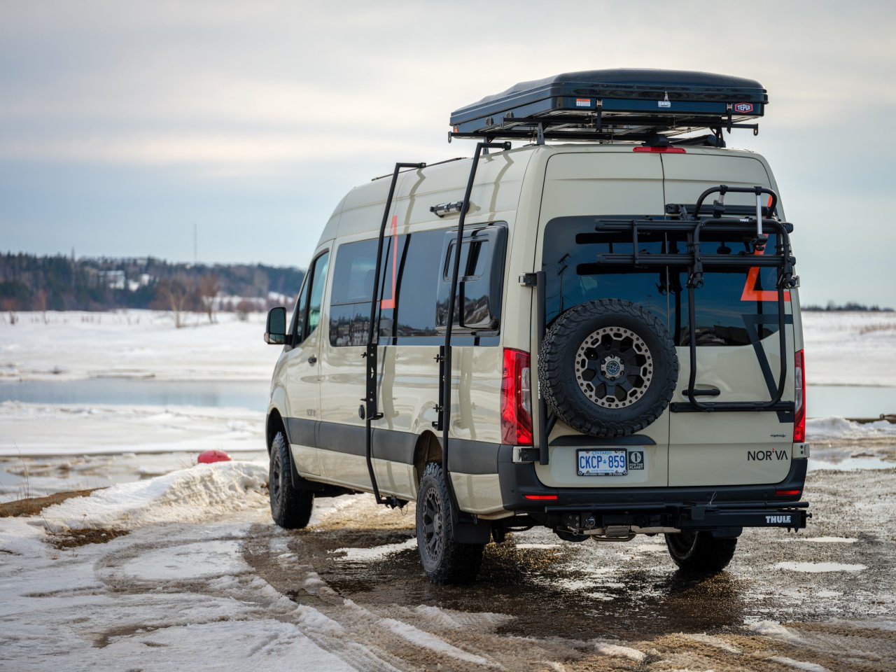 The rear of the camper van has a load door bike rack, a hitch rack and an Owl Vans spare tire carrier