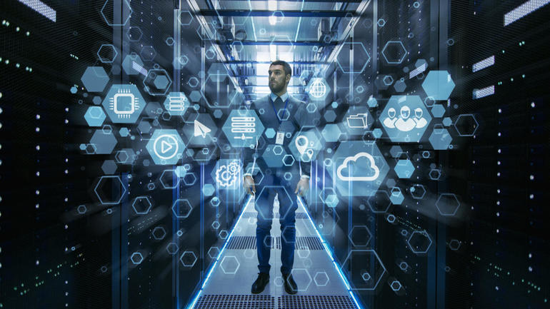 Curios IT Engineer Standing in the Middle of a Working Data Center Server Room. Cloud and Internet Icon Visualization in the Foreground.
