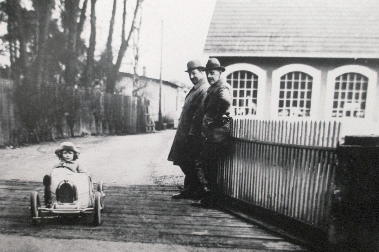 That's the original Bugatti Baby electric car being driven by Roland Bugatti with patriarch Ettore Bugatti and friend watching on - circa 1926.