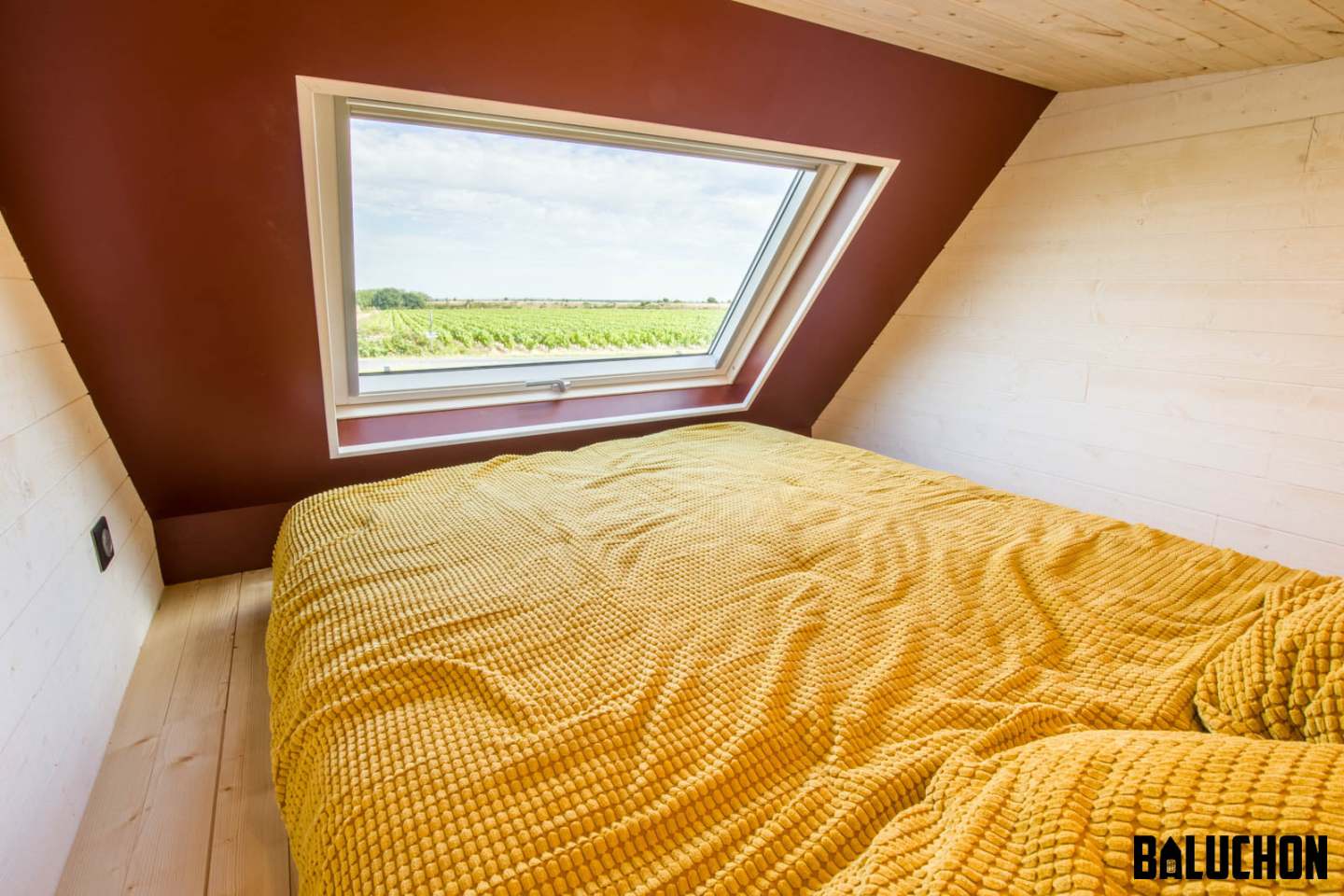 Tiny House Insoumise's bedroom is a typical tiny house-style loft bedroom with a low ceiling, and is topped by a generous skylight that frames the view