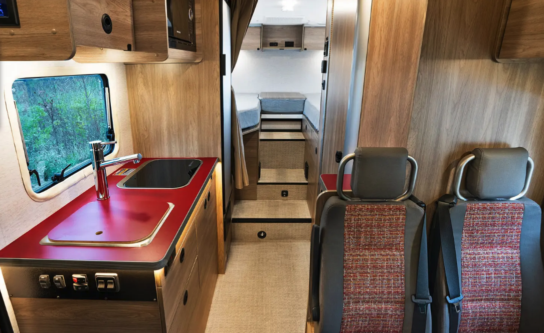 The interior layout is quite familiar from countless European camper vans and small motorhomes, furnished with a driver-side dinette, central kitchen and wet bath, and rear bedroom