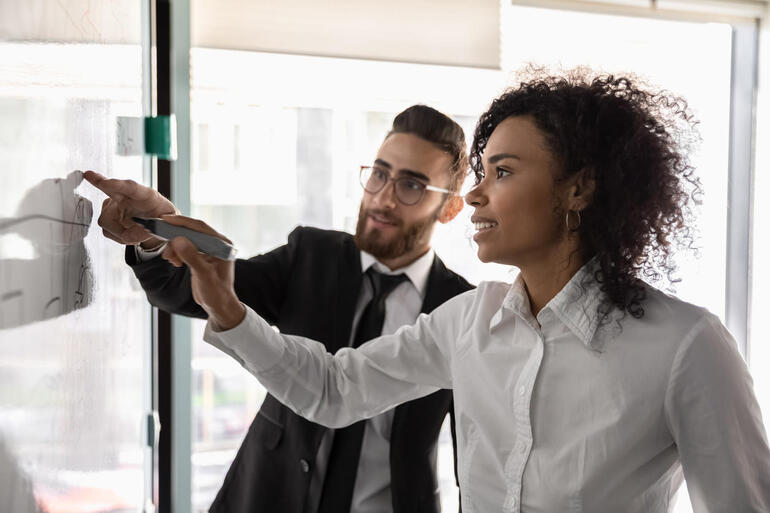 Multiethnic businesspeople develop business strategy on whiteboard