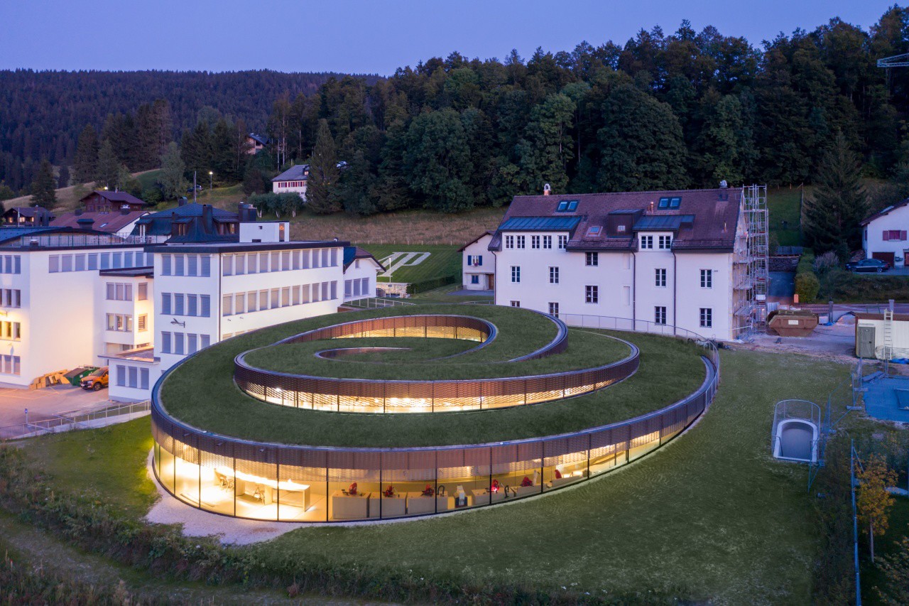 Musée Atelier Audemars Piguet, by BIG, is defined by an attractive spiraling design and is topped by a green roof that helps it take its place well amid the rolling Swiss landscape