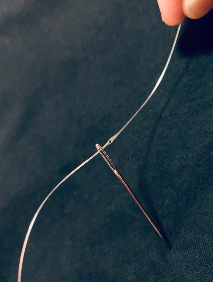 A close-up image of the digital fiber threading the eye of a needle