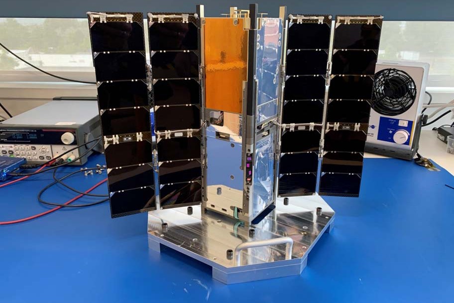 A CubeSat Networked Communications Experiment Block 1 satellite is shown with solar arrays