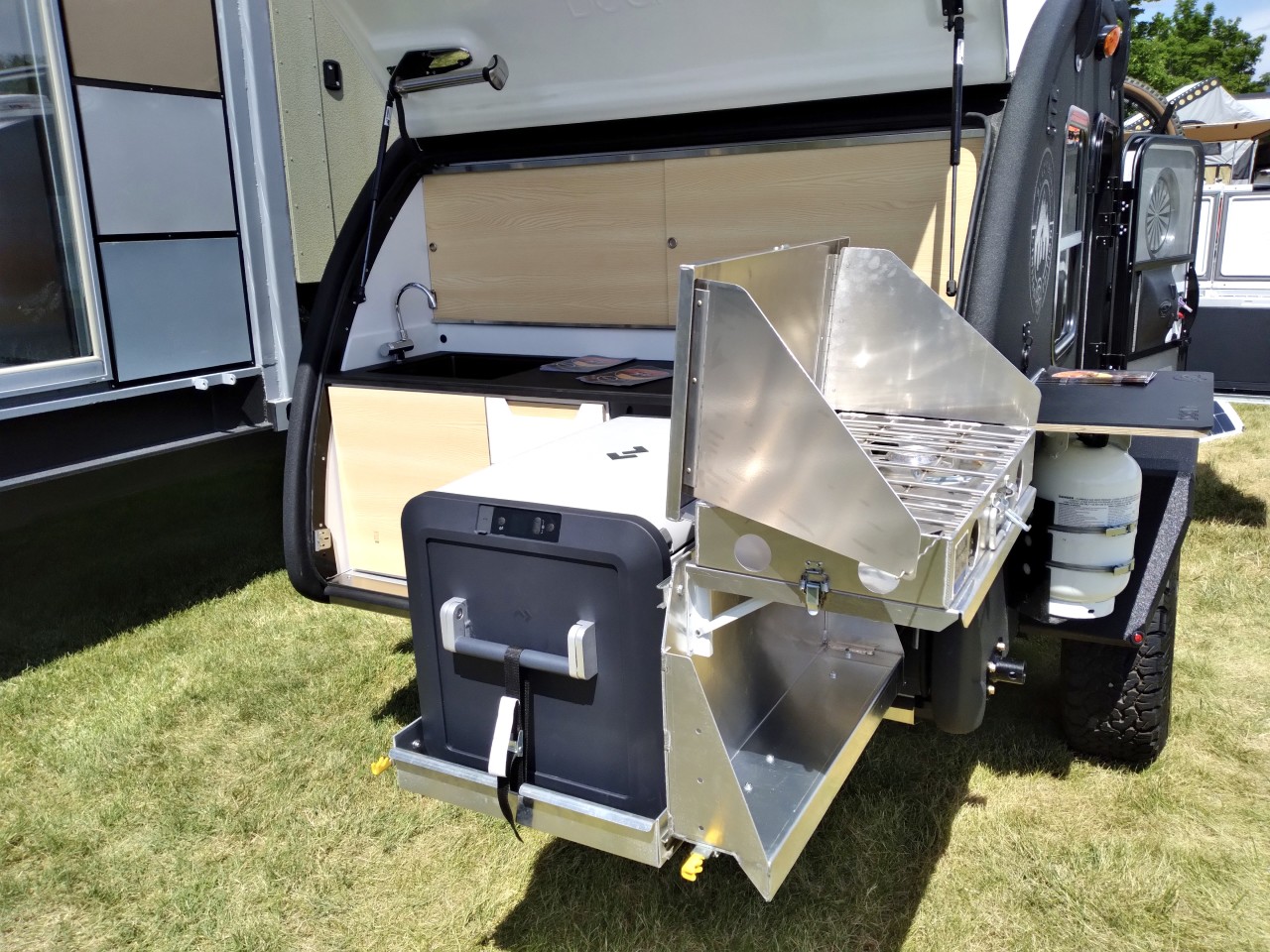 The fold-and-slide stove fits vertically next to the fridge and then flips up to work on the side of the trailer or under the tailgate (it's on a separate slide so cooks won't have the fridge in their way)