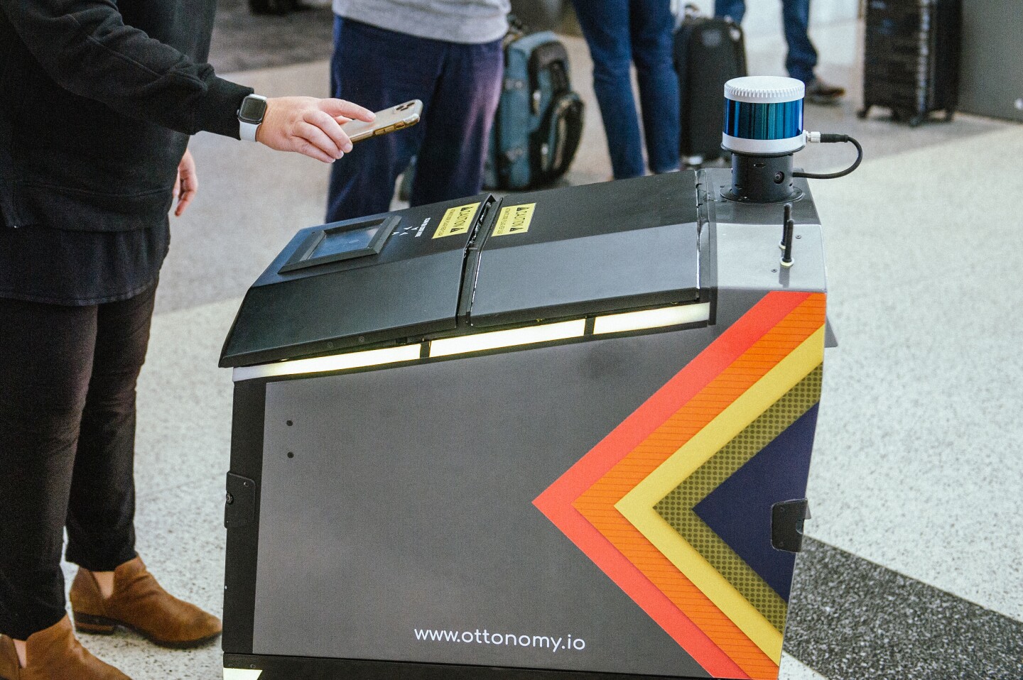 A customer holds their order-specific QR code up to an Ottobot's scanner