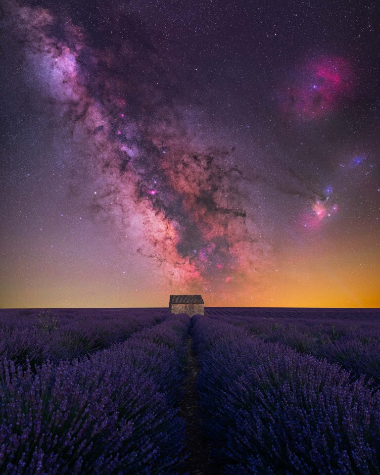 House of Lavender. A pink-toned Milky Way looms over a lavender field in France, with natural lines guiding the eye towards a lonely cabin in the center