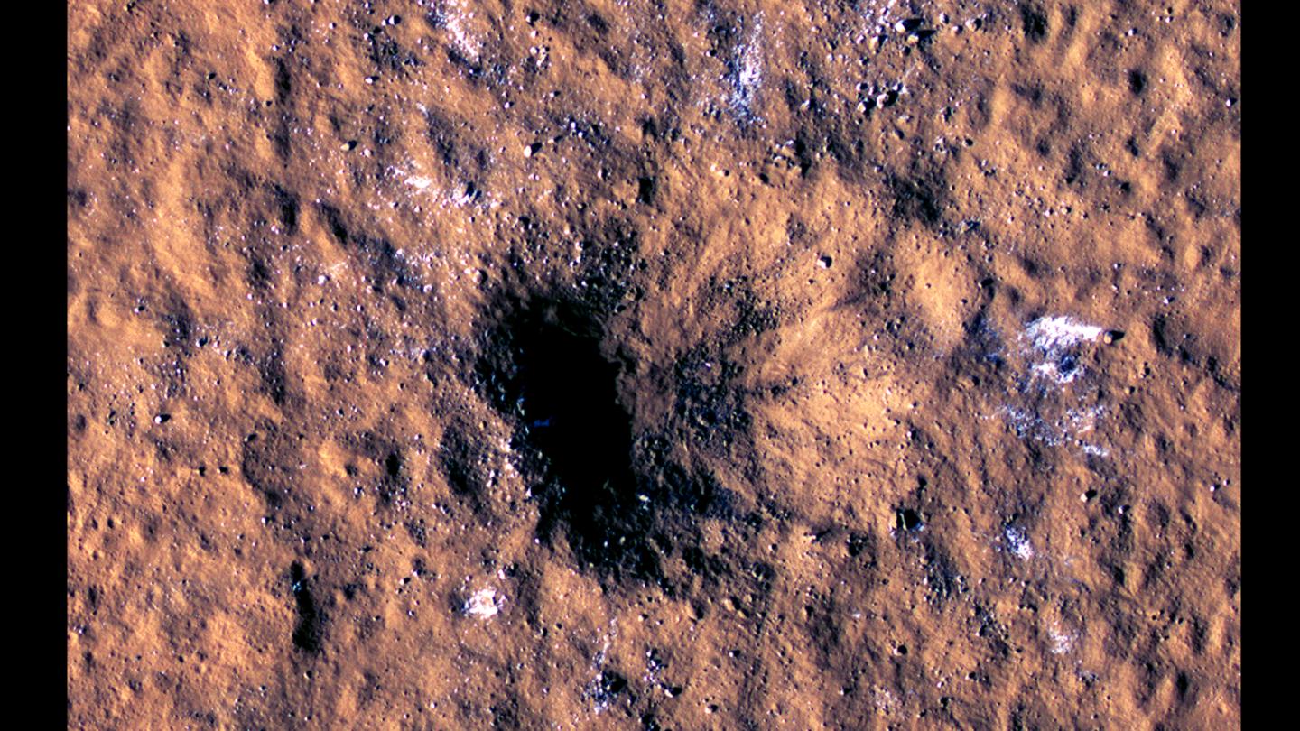 The new impact crater, as seen by the Mars Reconnaissance Orbiter. White spots indicate chunks of water ice thrown loose from beneath the surface