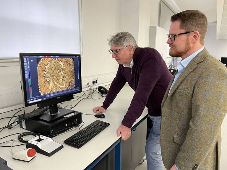 Professor Paul N. Pearson and Jesper Ericsson examine the Sponsian gold coin under a powerful microscope