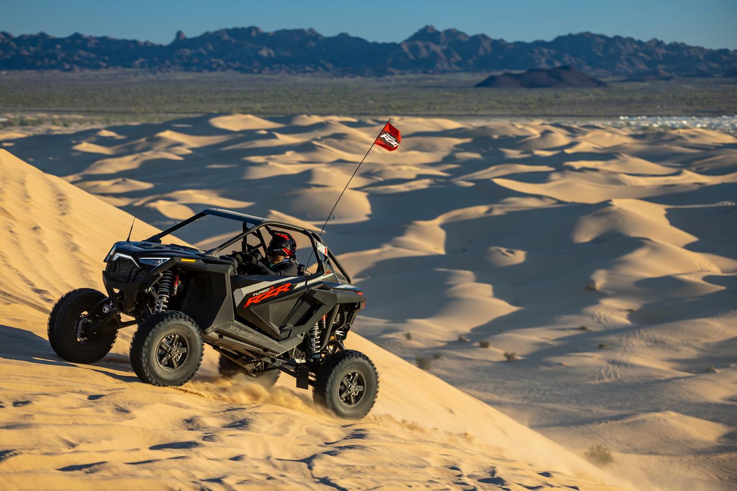 The author climbs Oldsmobile Hill, one of the largest dunes near Glamis. In the background, the edge of Camp RZR's RV parking area can be seen
