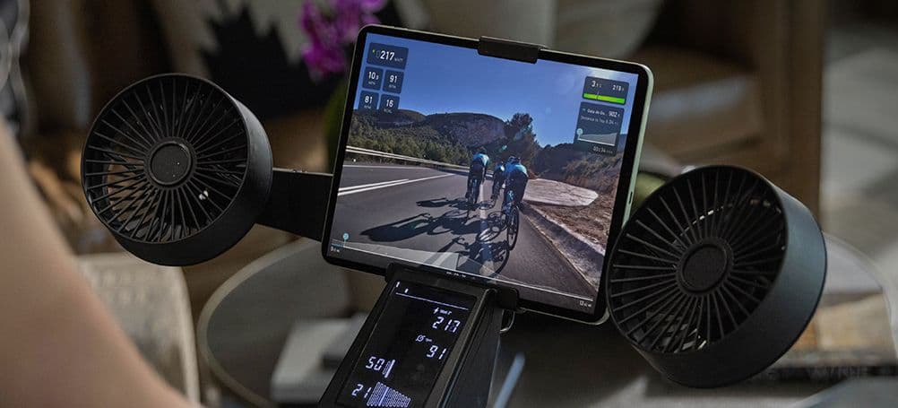 The Tacx NEO Bike Plus features an integrated display for at-a-glance performance data, a tablet can be mounted up front to show workouts and real-world courses, and there are two fans to keep riders cool when the training session heats up