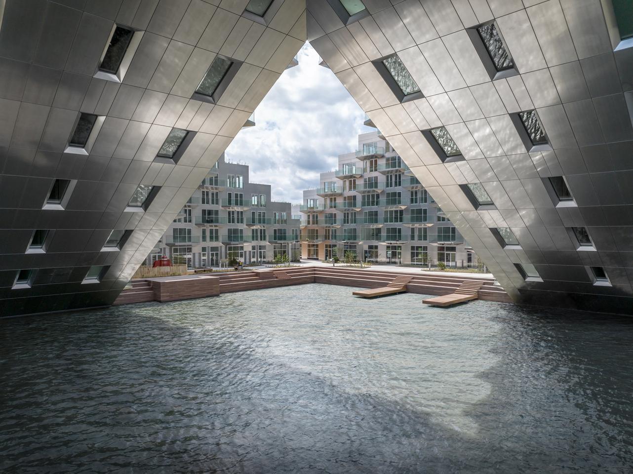 Sluishuis features a striking aluminum-clad facade which reflects the water from the lake, while its rooftop terrace areas and courtyard are decked out in timber