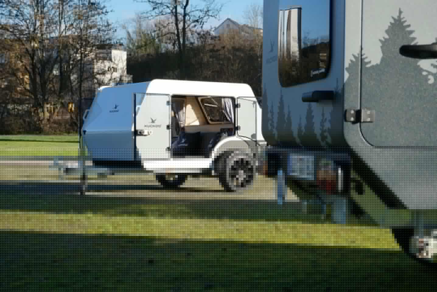 The Kuckoo Emma squaredrop trailer peeks out to show one of its large, glass-doored entries