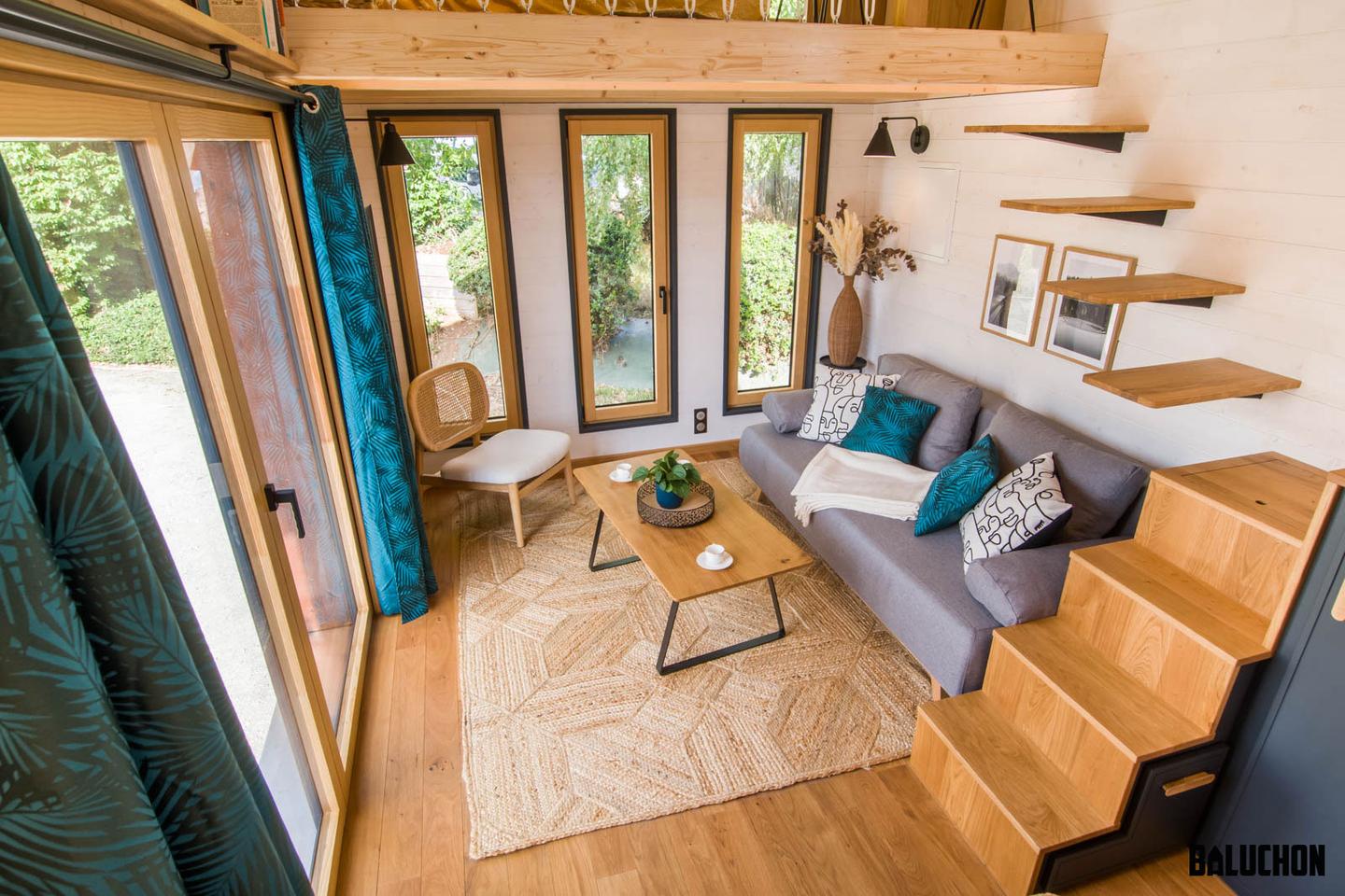 The Gaïa Tiny House's living room includes a sofa bed, chair, and coffee table