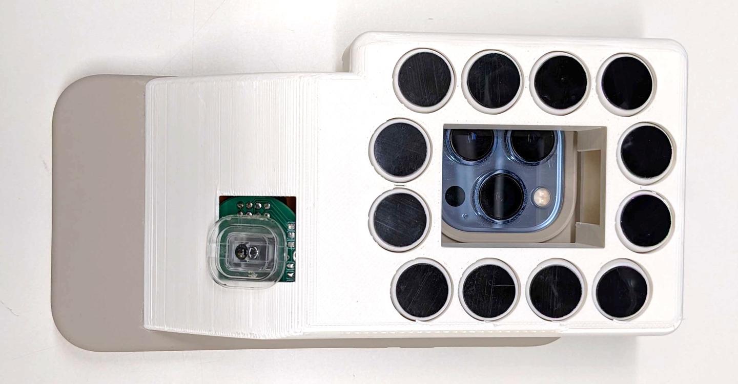 The underside of the BrushLens device, with the autoclickers surrounding the phone camera window – another version uses mechanical pushbuttons instead of autoclickers