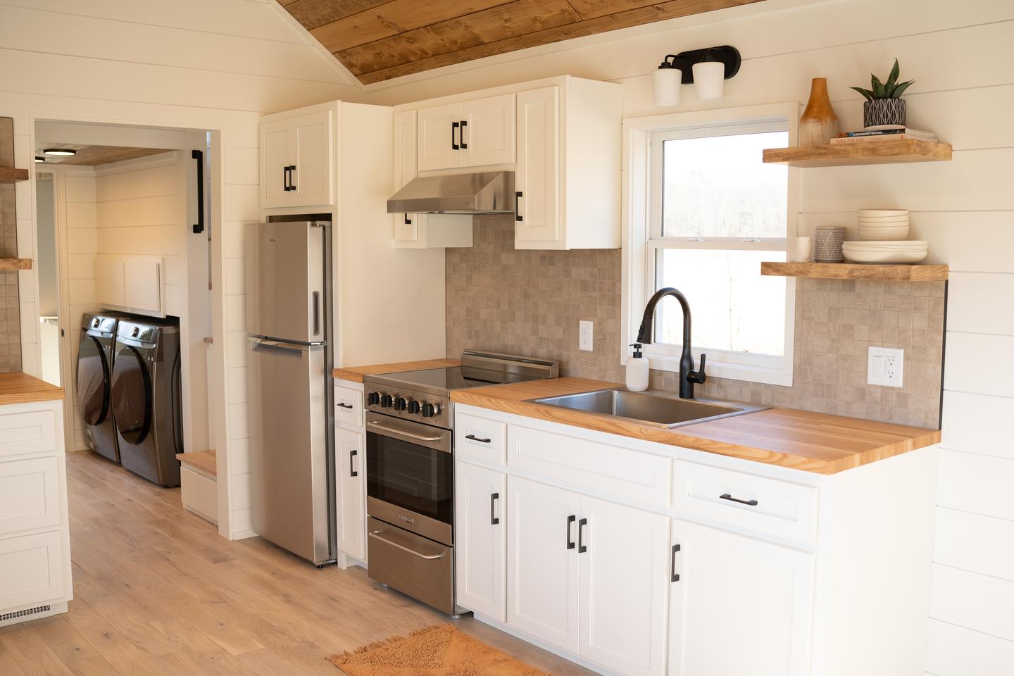 The Tellico's kitchen is quite well-stocked for a tiny house and includes a fridge/freezer, sink, dishwasher, radiant cooktop and cabinetry
