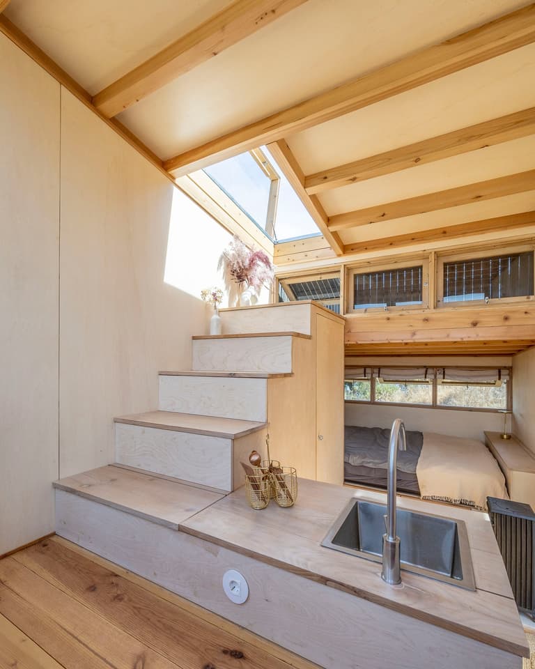 The Terra m2_Tiny House on Wheels' storage-integrated steps lead up to its rooftop terrace area