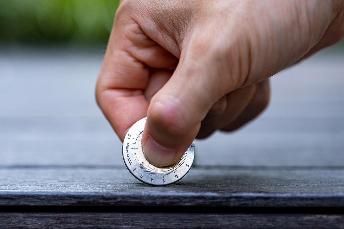 The device is held by its inner ring and rolled like a wheel when measuring items