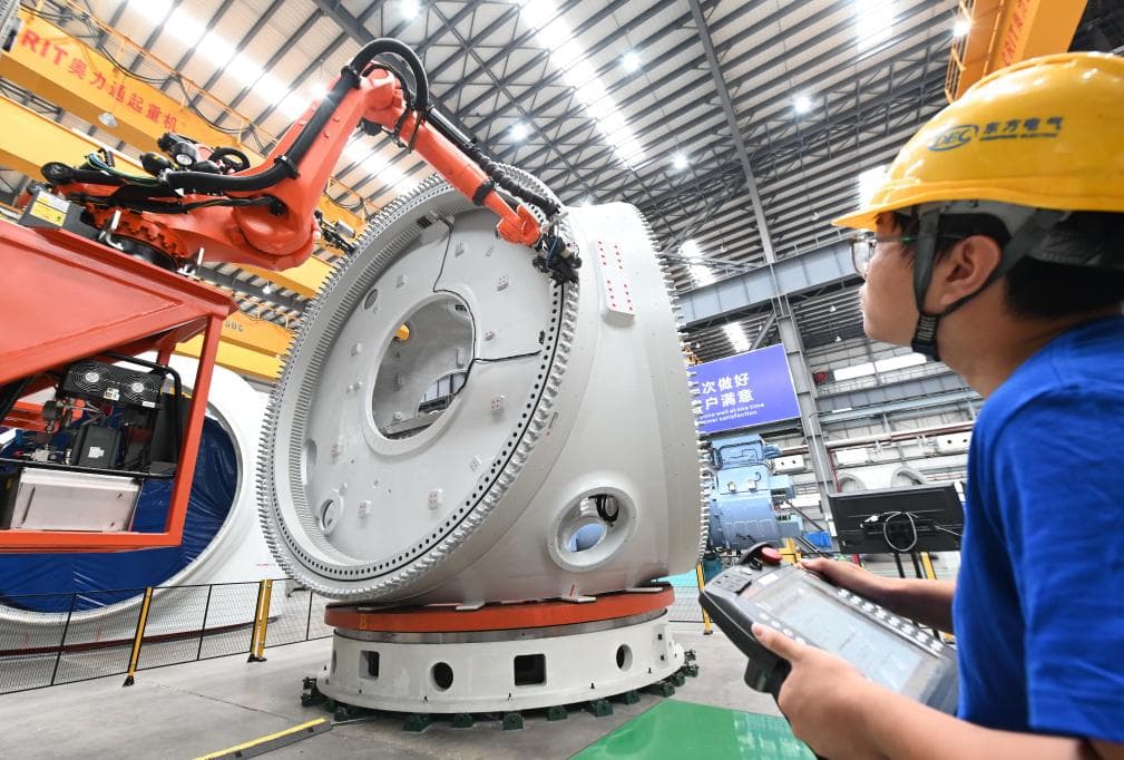 A tech at Dongfang's factory operates a robotic arm while assembling the 26 MW wind turbine components