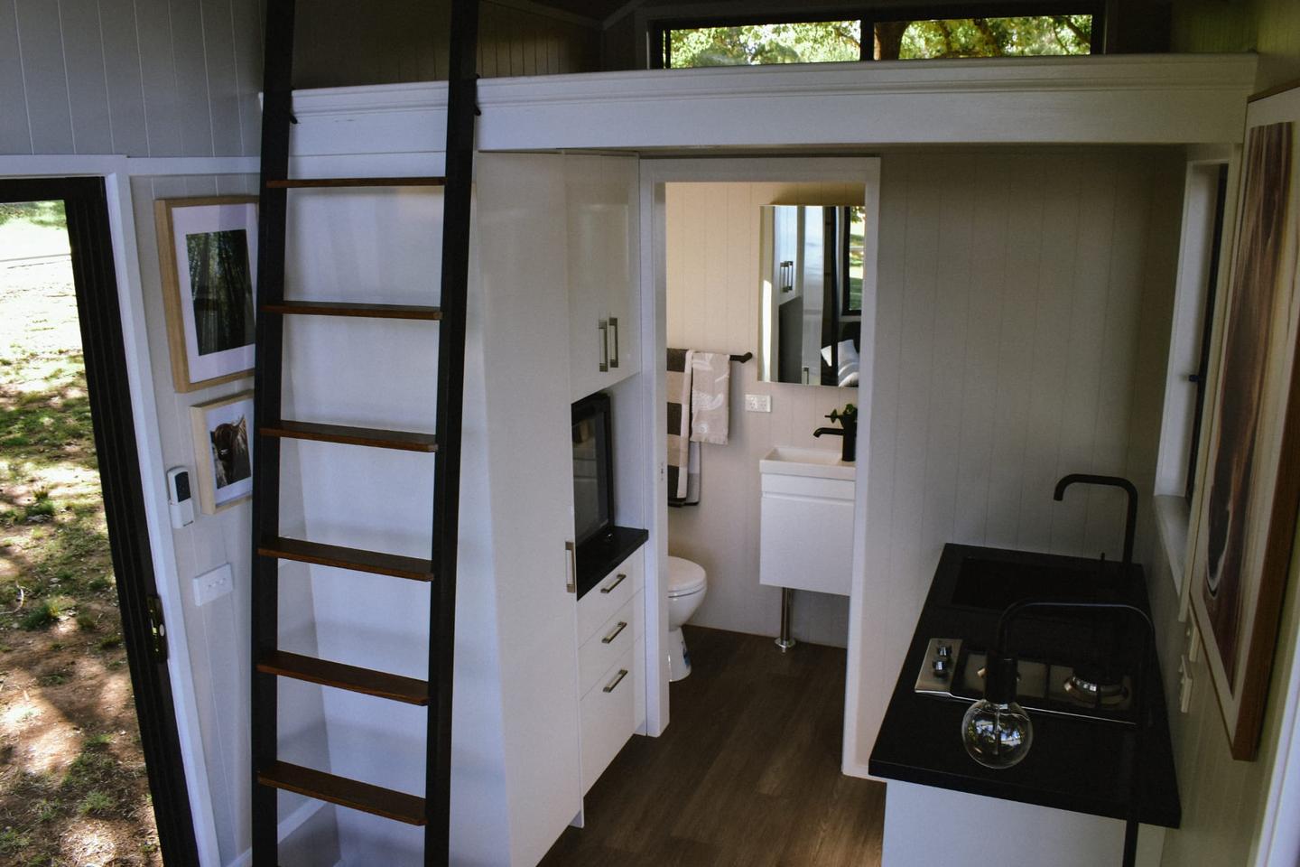 The 4800L Compact's kitchen includes a sink, two-burner propane-powered stove, and a microwave, plus cabinetry