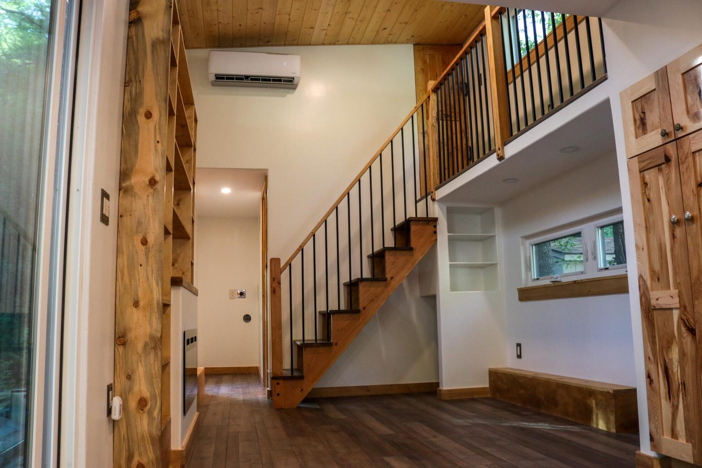 The Felicity 10' Wide tiny house's living room includes space for a sofa, as well as an electric fireplace