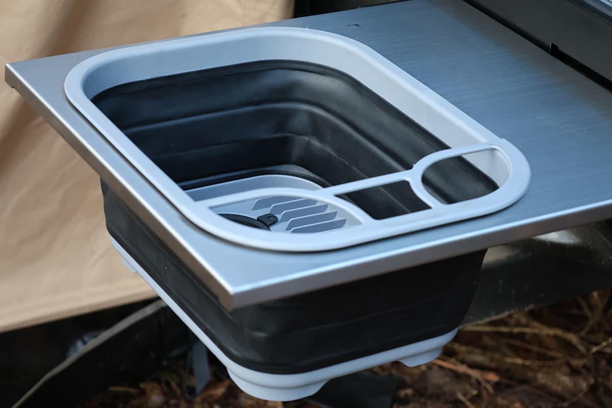 A roller drawer hides away this collapsible sink, as well as a three-burner gas stove