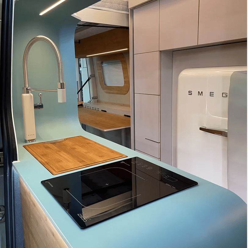 Tall Smeg faucet, rectangular stainless steel sink with bamboo cutting board top, and induction cooktop
