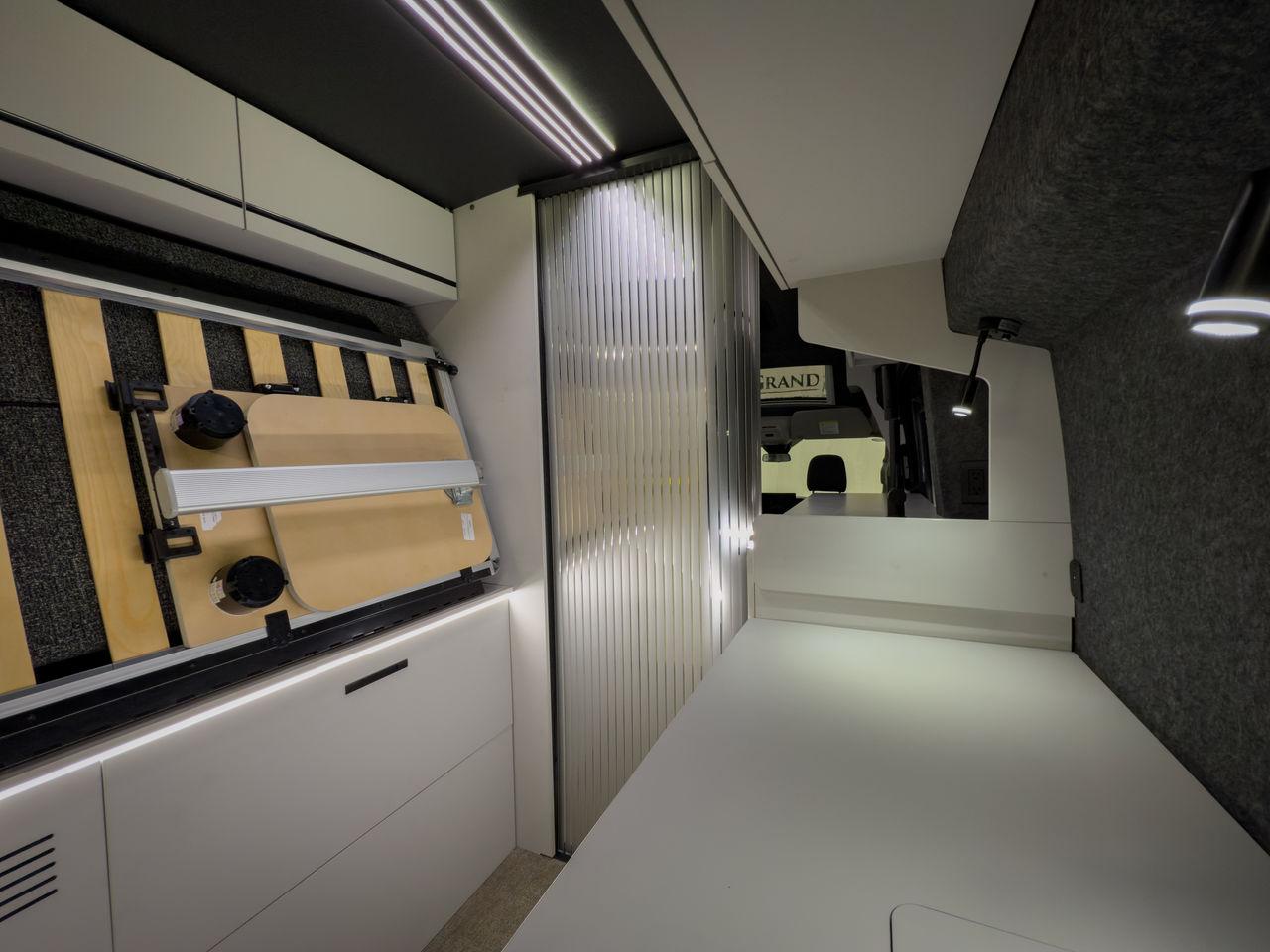 The center of the bed folds up, leaving a side shelf/work area console; the dining table mounts to the underside of the bed when not in use