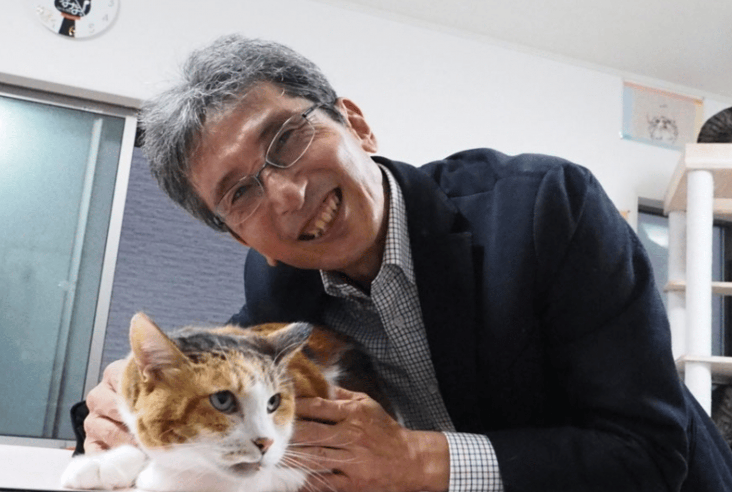 Professor Hiroyuki Sasaki, a geneticist at Kyushu University, makes friends with one of the calico cats at a local shelter during his research